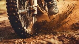 Close up of a dirt bike's rugged tire kicking up dirt on a dirt trail, showcasing the gritty and adventurous spirit