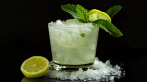 A refreshing mint infused cocktail served in a frosty glass, garnished with a sprig of fresh mint and a slice of lemon