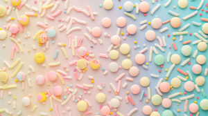 A collection of diverse sprinkle shapes and sizes in vibrant colors forms a repeating pattern against a gentle pastel background