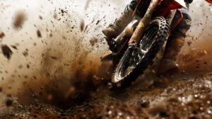 Experience the excitement of off road racing with a wallpaper featuring a dirt bike speeding through a muddy trail dirt flying up and the rider leaning into a sharp turn