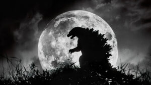 A striking wallpaper of Godzillas silhouette in black and white against a full moon capturing an iconic and dramatic scene