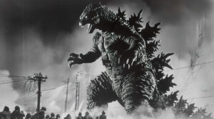 Godzilla seen from below, giving a sense of its immense size as it towers over a crowd of fleeing people