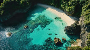 A wallpaper showcasing a hidden beach cove enclosed by verdant cliffs and crystal clear aquamarine waters from an aerial perspective