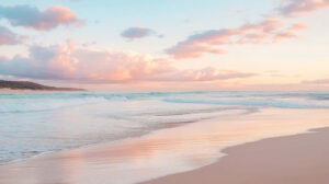 An aesthetic beach scene with pastel skies at sunset, gentle waves lapping at the shore, and soft pink clouds